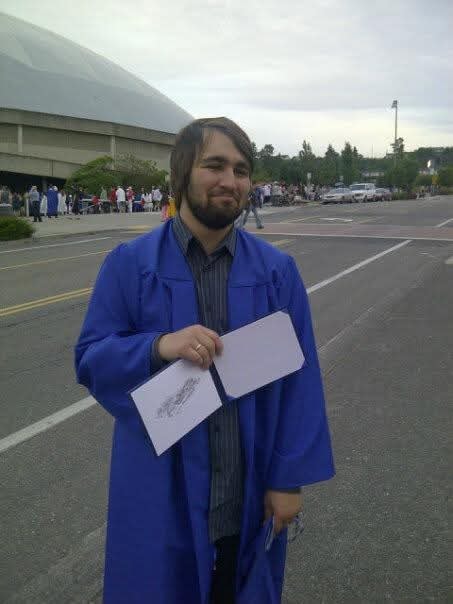Young man in graduation cap and gown holding diploma