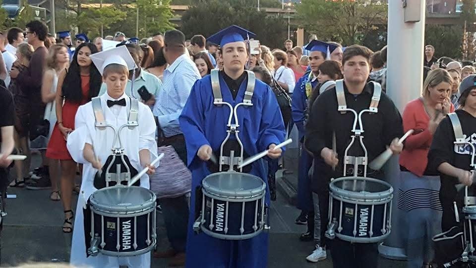 Graduates in caps and gowns marching with drums