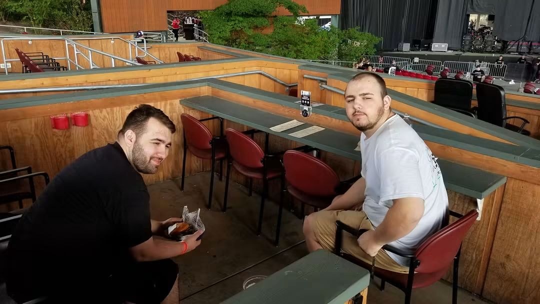 Two young men sitting at an outdoor music venue