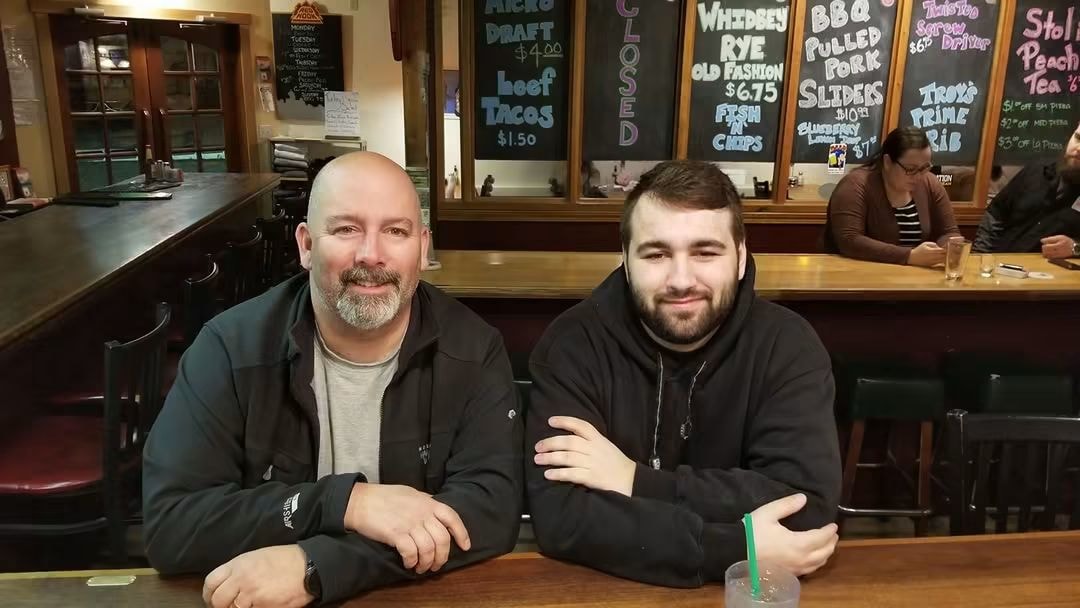 Father and son smiling together at a bar
