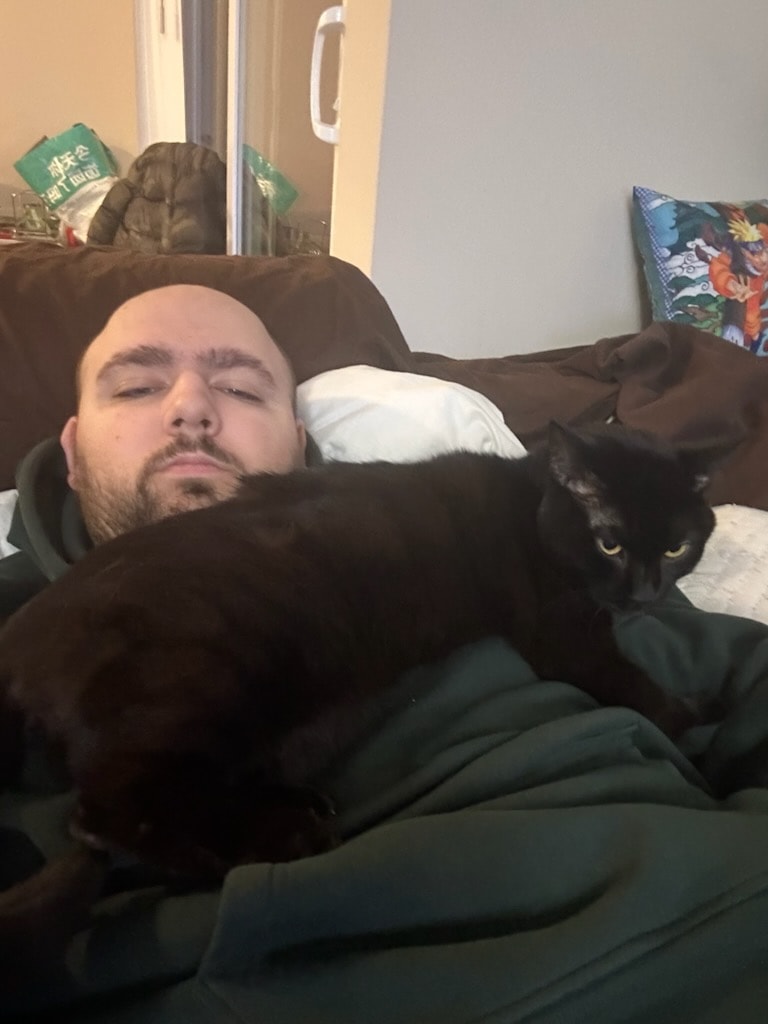 Man resting on a couch with a black cat