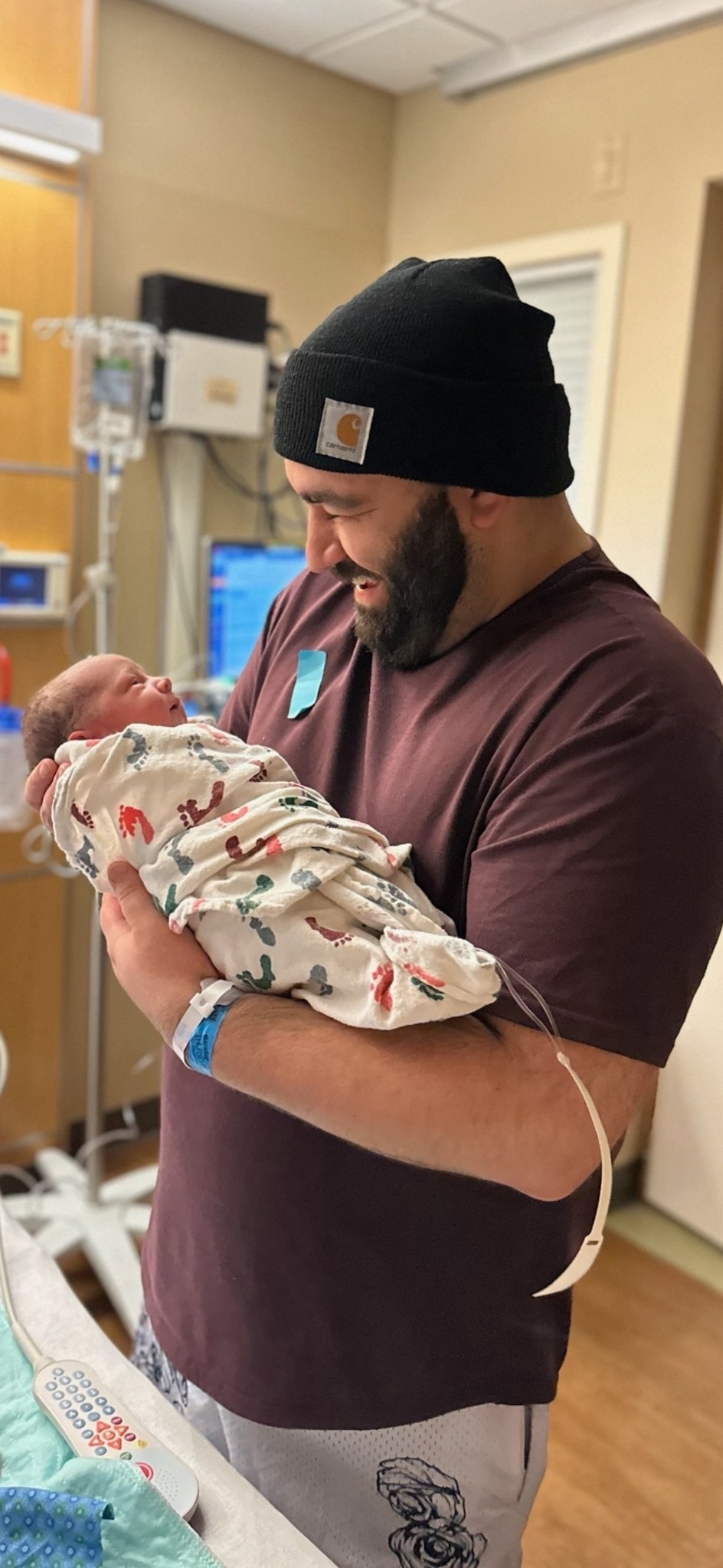 Man holding a newborn baby in a hospital room
