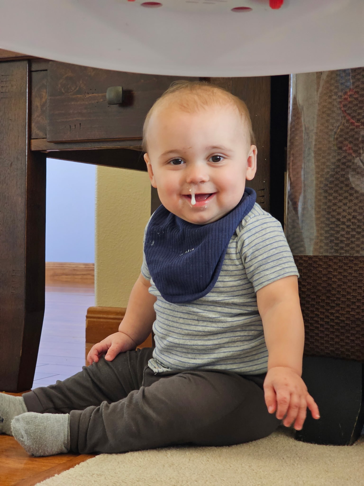 Smiling baby sitting on the floor with a bib
