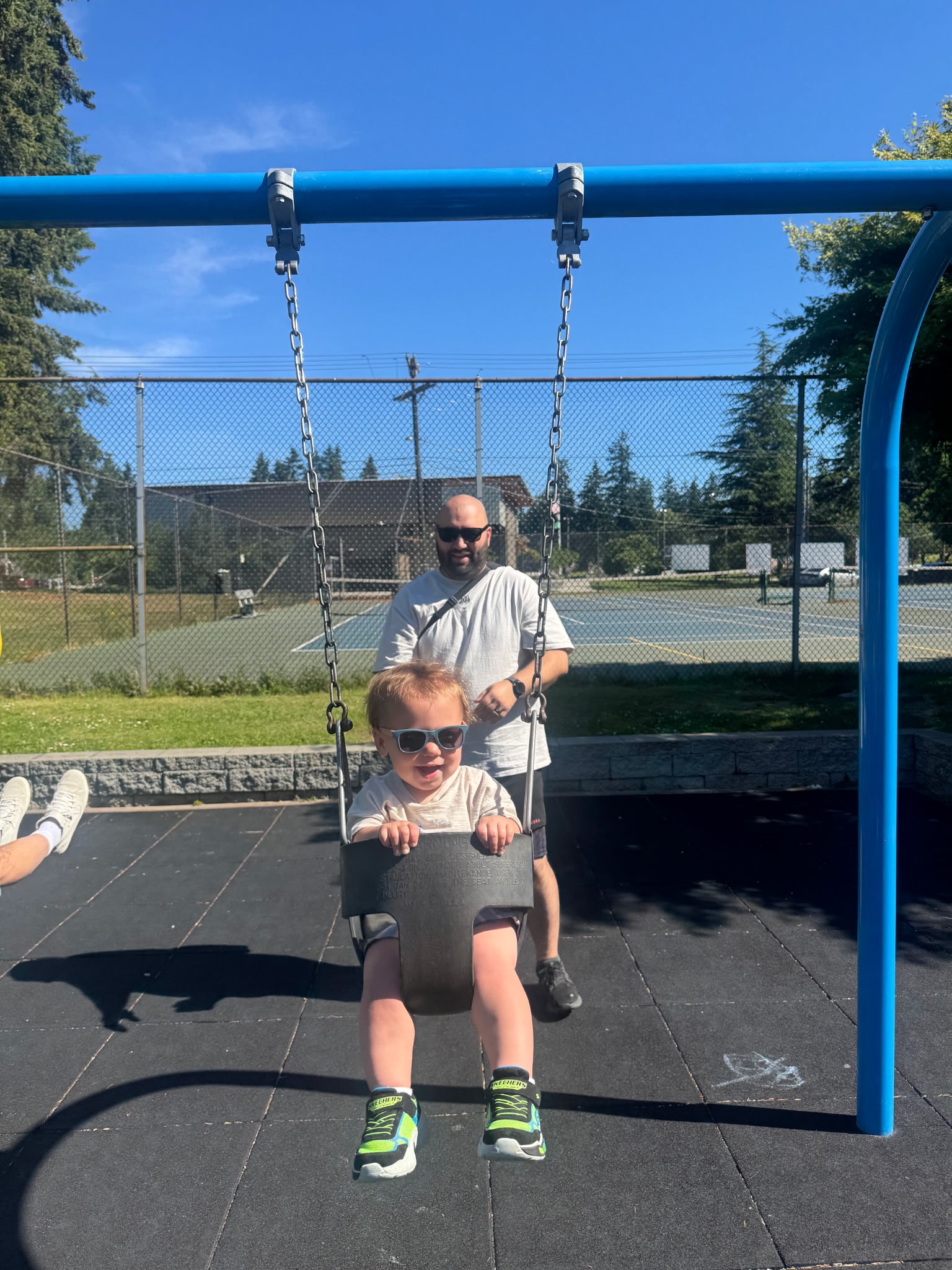 Father pushing toddler on a swing at a playground