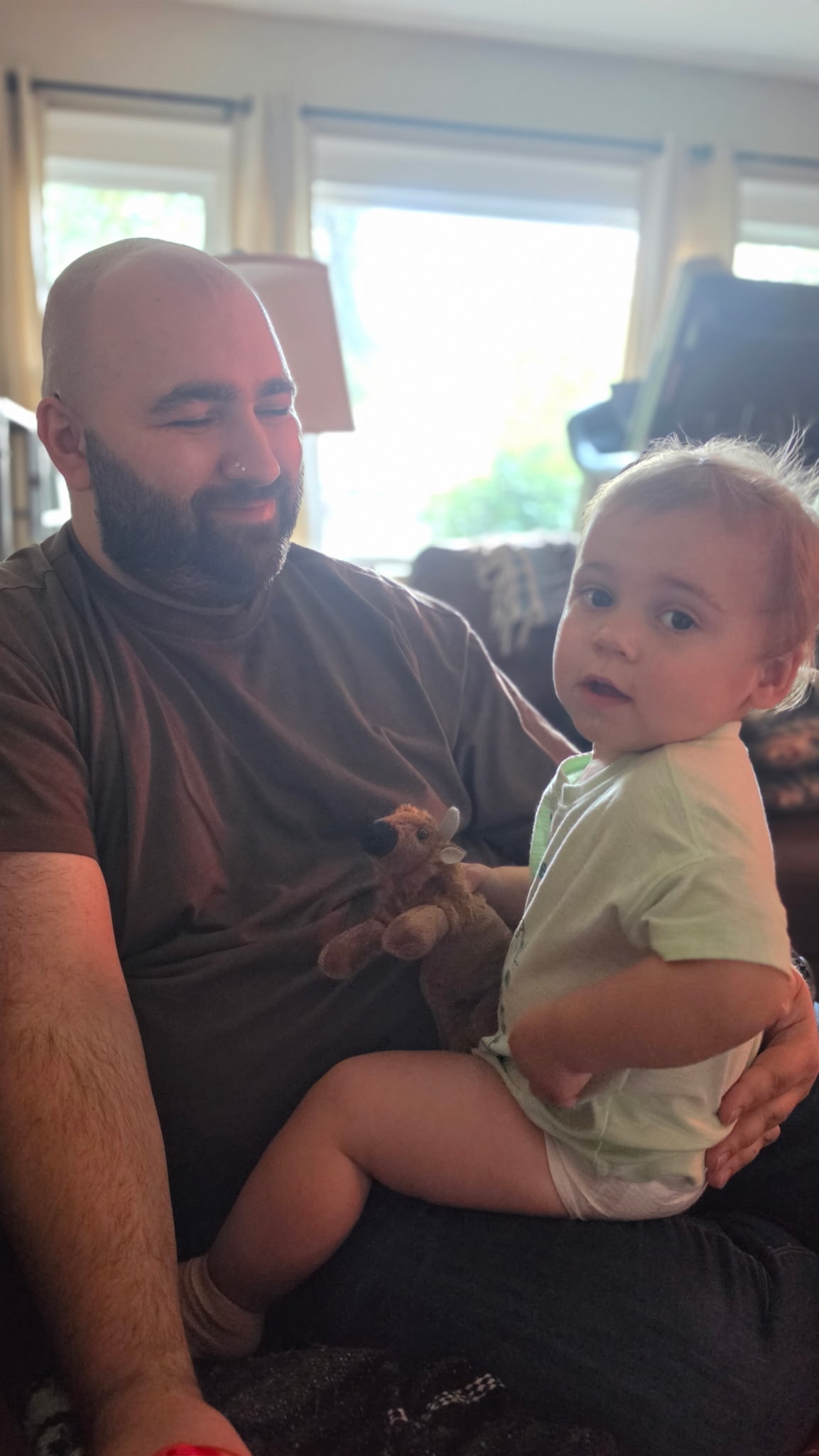Father sitting with baby holding a stuffed deer toy