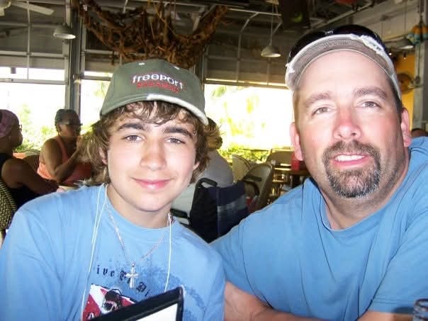 Father and teenage son smiling together at a restaurant