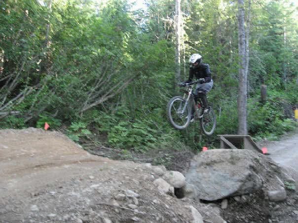 Mountain biker launching off a jump on a dirt trail