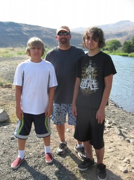 Father and two teenage sons standing by a river