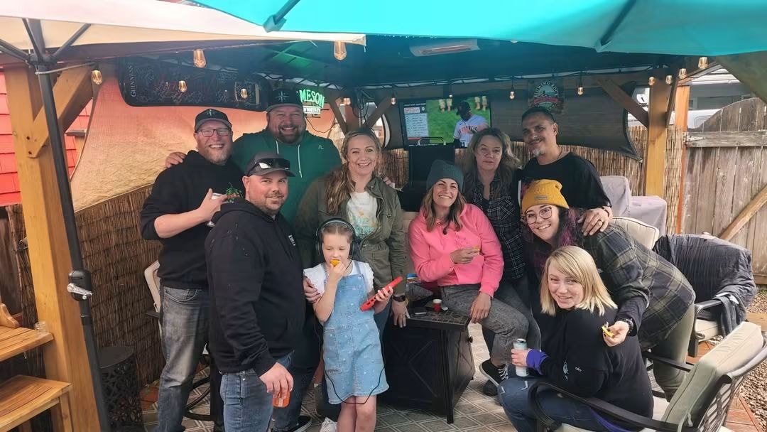 Group of friends gathered under a backyard patio with string lights