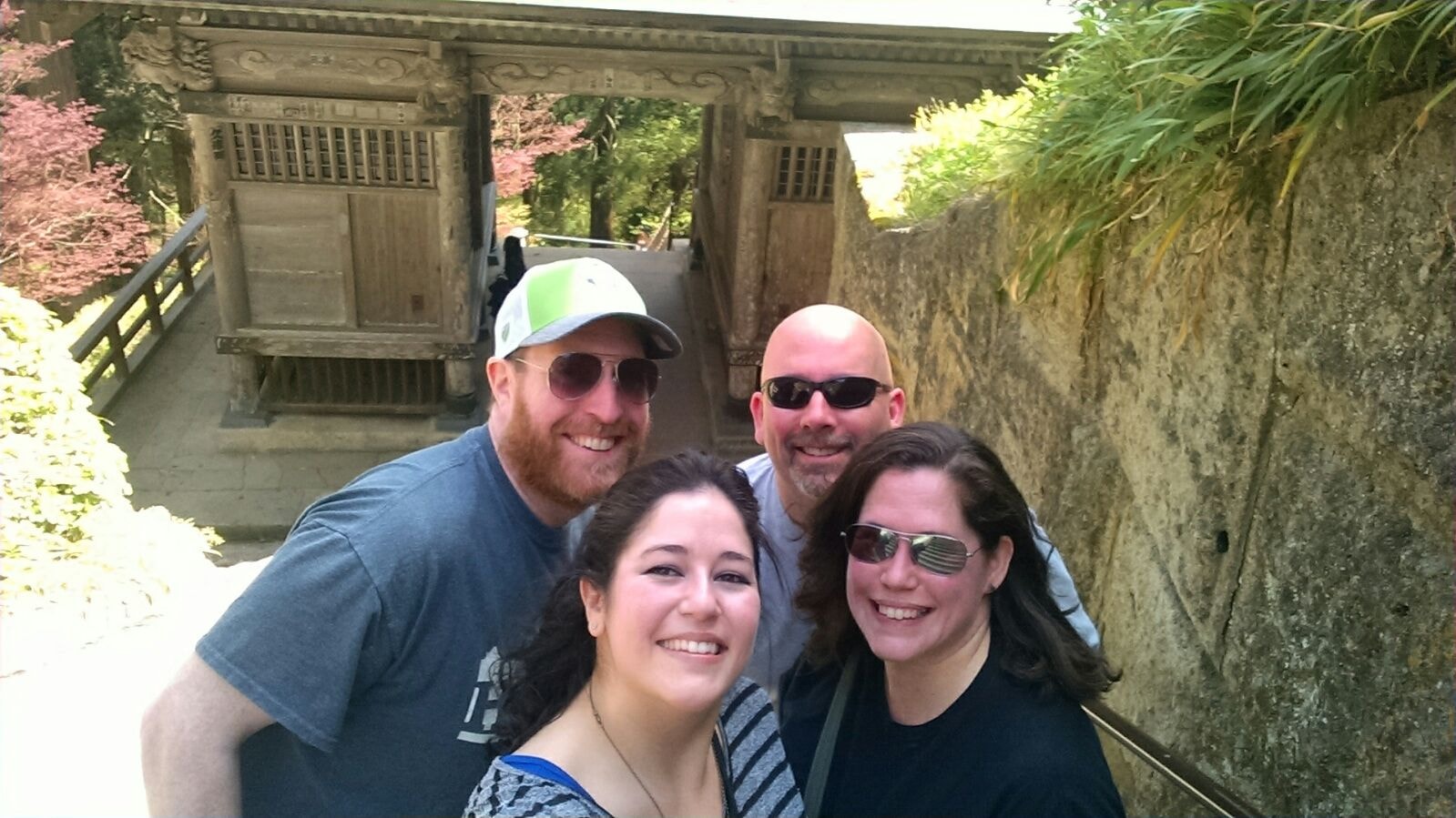Four friends smiling at a Japanese temple garden gate